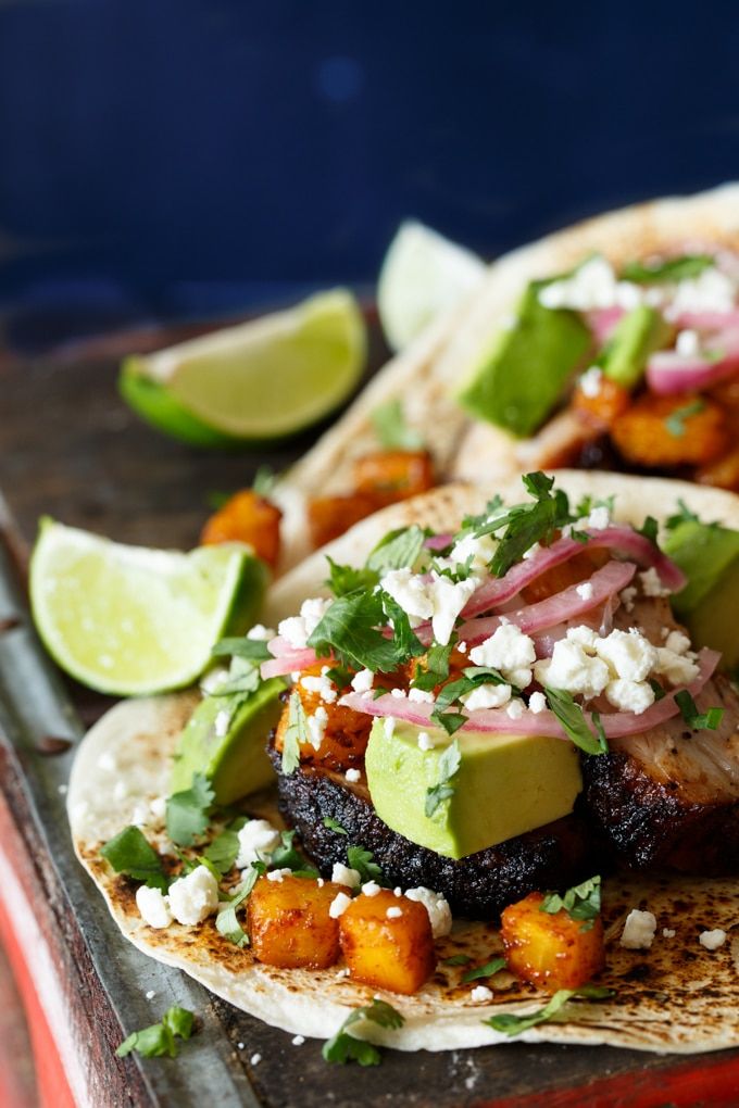 three tacos with meat, avocado, and cilantro on them