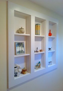 three white shelves with pictures and vases on them in the corner of a room