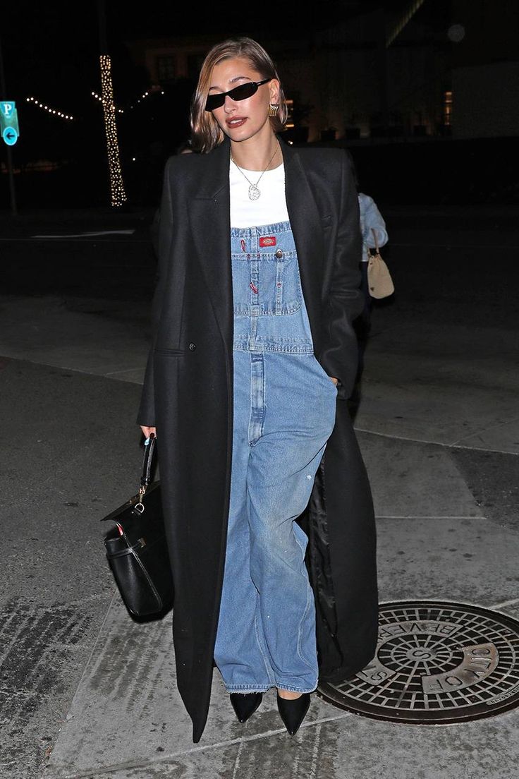 a woman in overalls is walking down the street