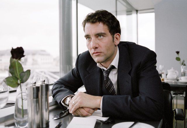 a man in a suit sitting at a table with his arms crossed and looking off to the side