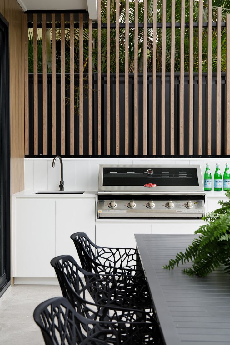 an outdoor kitchen with grill, table and chairs