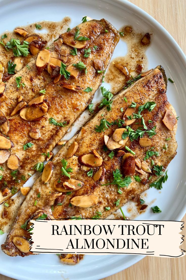 two pieces of fish on a white plate with almonds and parsley sprig