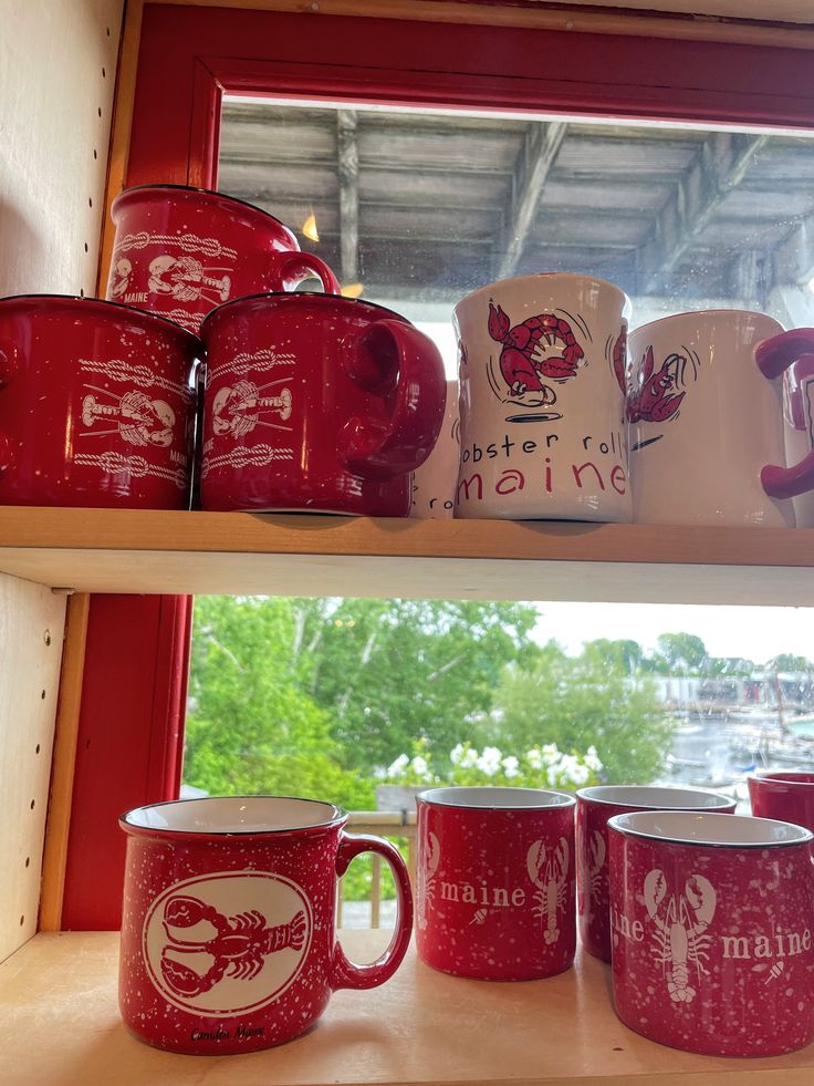 red and white coffee mugs sitting on top of a shelf