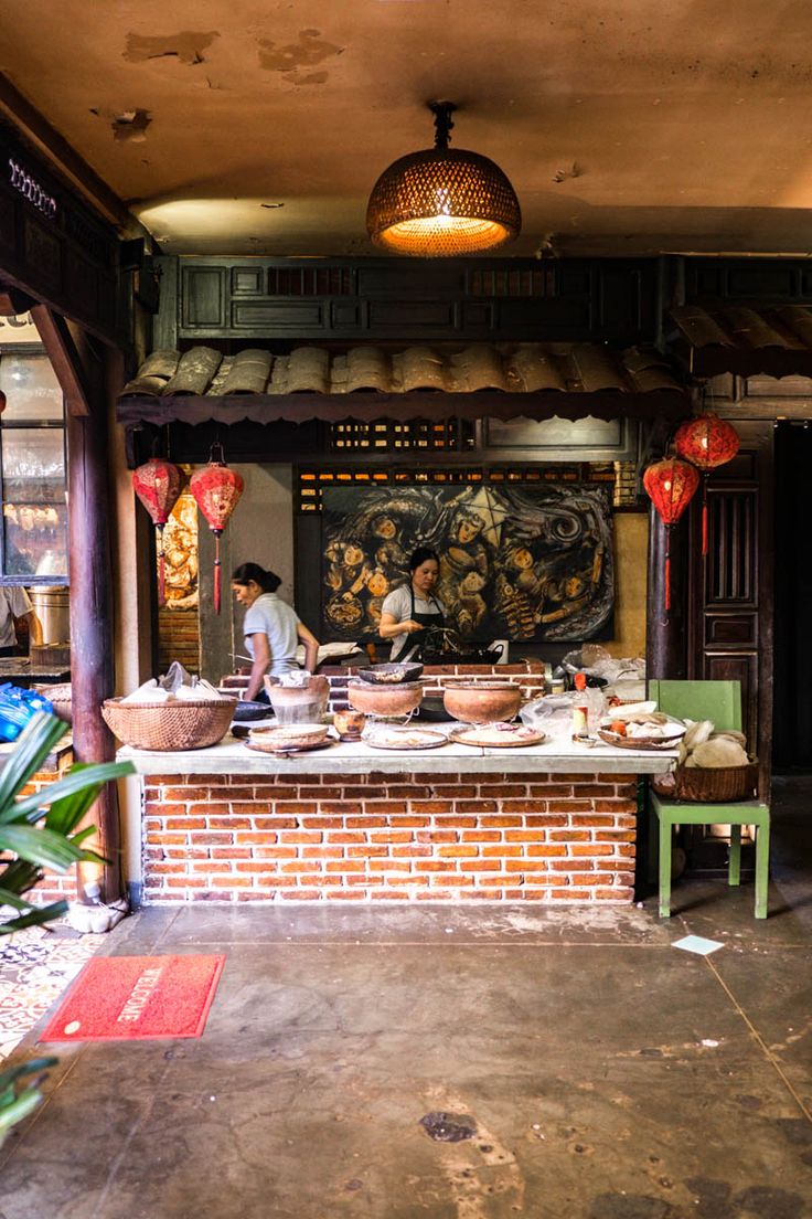 a man preparing food inside of a kitchen on top of a brick counter next to potted plants