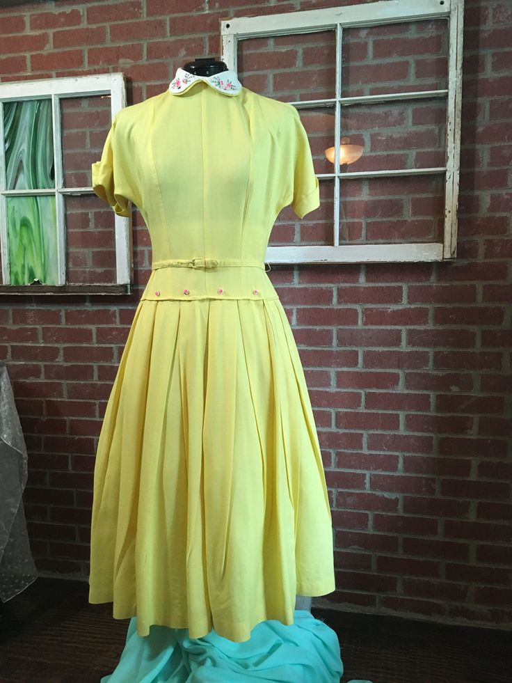 This charming and sophisticated vintage yellow cotton day dress, authentic from the 1940's, is the perfect attire for stepping out in the afternoon. Whether for the library, museum, or luncheon, the classy silhouette and design of this piece is a staple for any vintage closet. Accents include a Peter Pan collar decorated with silver studs and pink flower beads, more pink flower beads on the front of the waist, sailor-rolled sleeves, a matching belt, and pleats at the hips of the dress. Complete Yellow Vintage Dress, 1940s Fashion Women, Forties Fashion, Banana Yellow, Vintage Closet, Fashion 1950s, Flower Beads, 1940s Fashion, Lovely Clothes