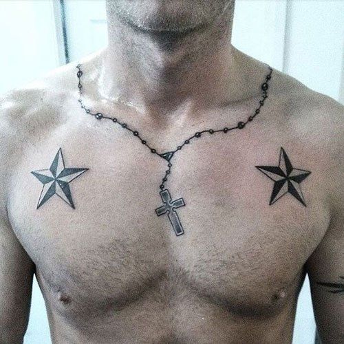 a shirtless man with tattoos on his chest holding a cross and two star necklace