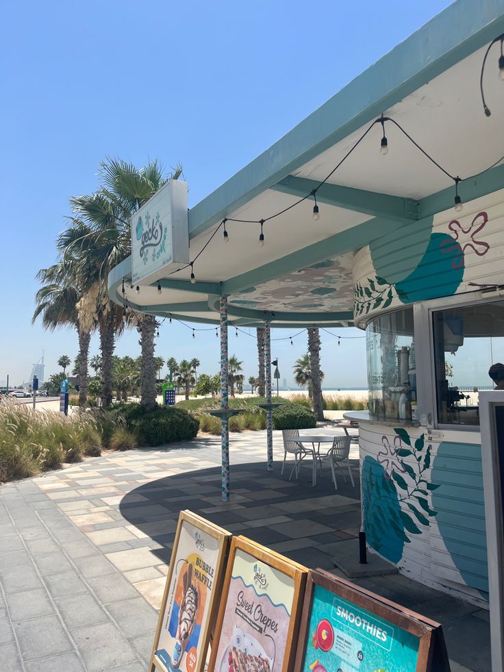 there are some signs on the sidewalk by the beach