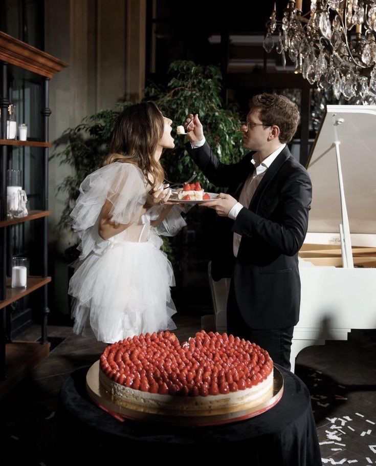 a bride and groom feeding each other cake at their wedding reception in front of a grand piano