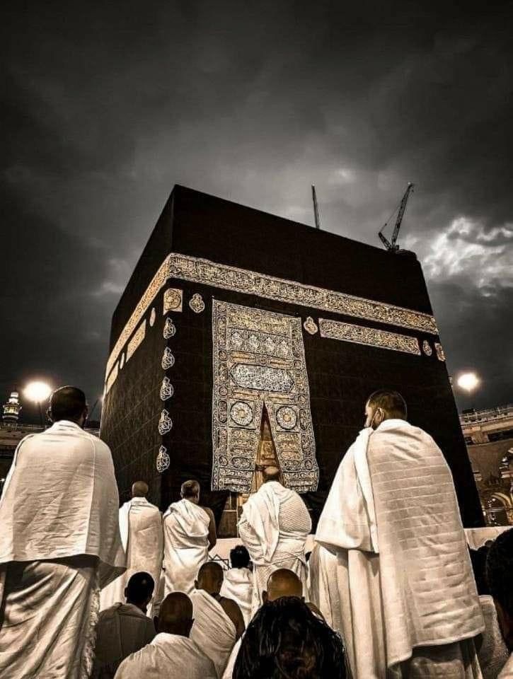 men in white robes standing around the base of a large building with an elaborately decorated door