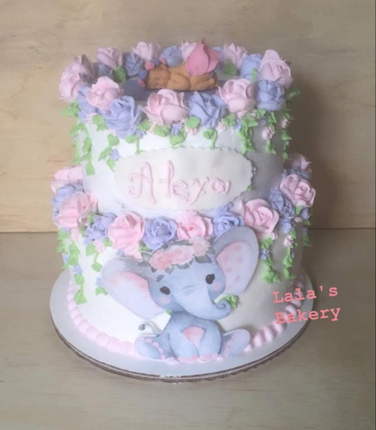 there is a cake that has an elephant on it and flowers around the bottom tier