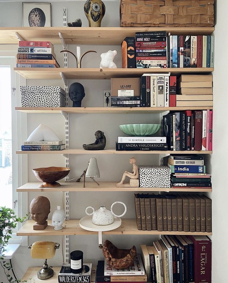 a bookshelf filled with lots of books next to a vase and potted plant