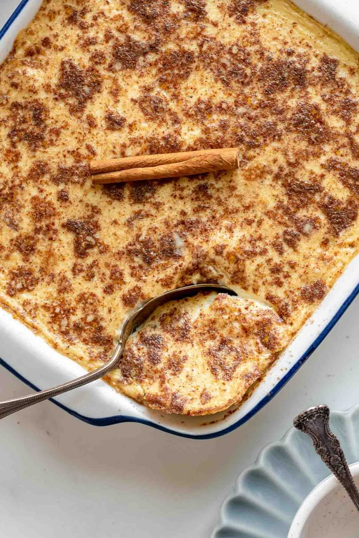 a casserole dish with cinnamon on top and spoon in the bowl next to it