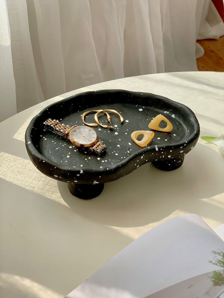 a black tray with gold scissors and other items on it sitting on a white table