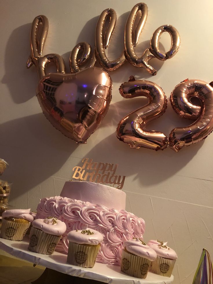 a birthday cake and cupcakes on a table with balloons in the shape of numbers