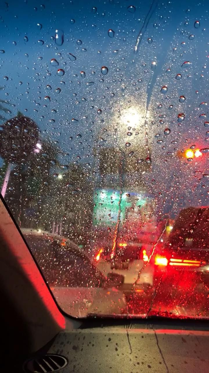 rain is falling on the windshield of a car