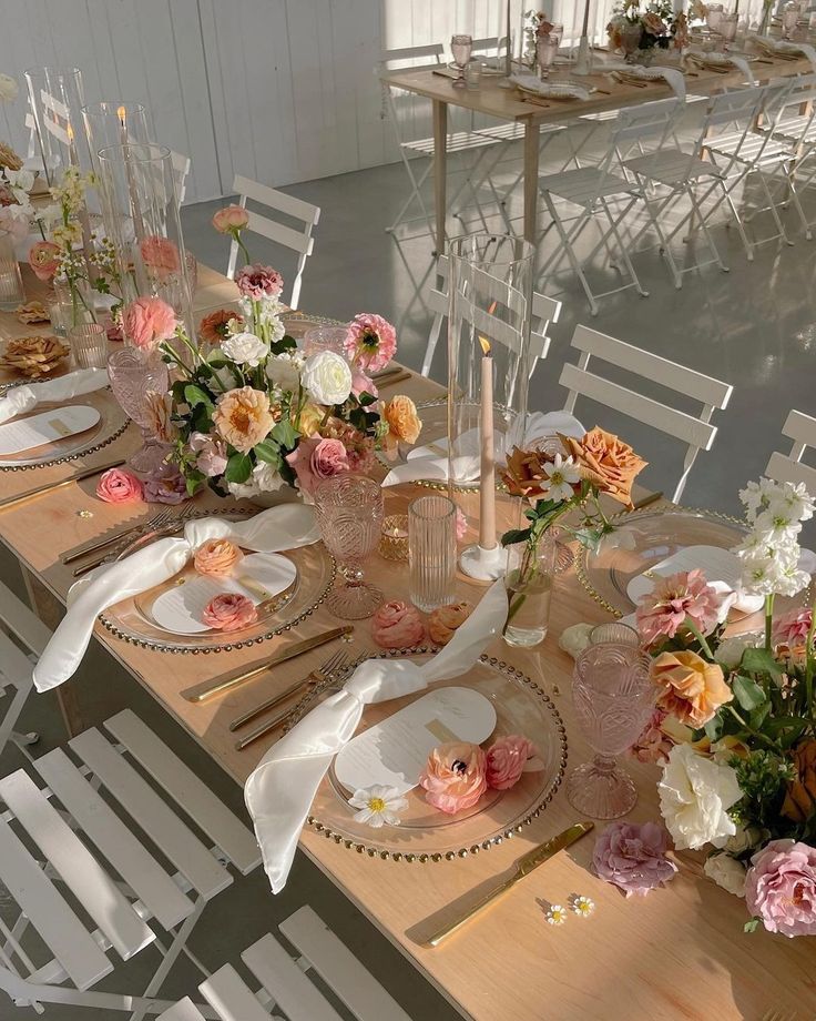 the table is set with plates and flowers on it, along with other place settings