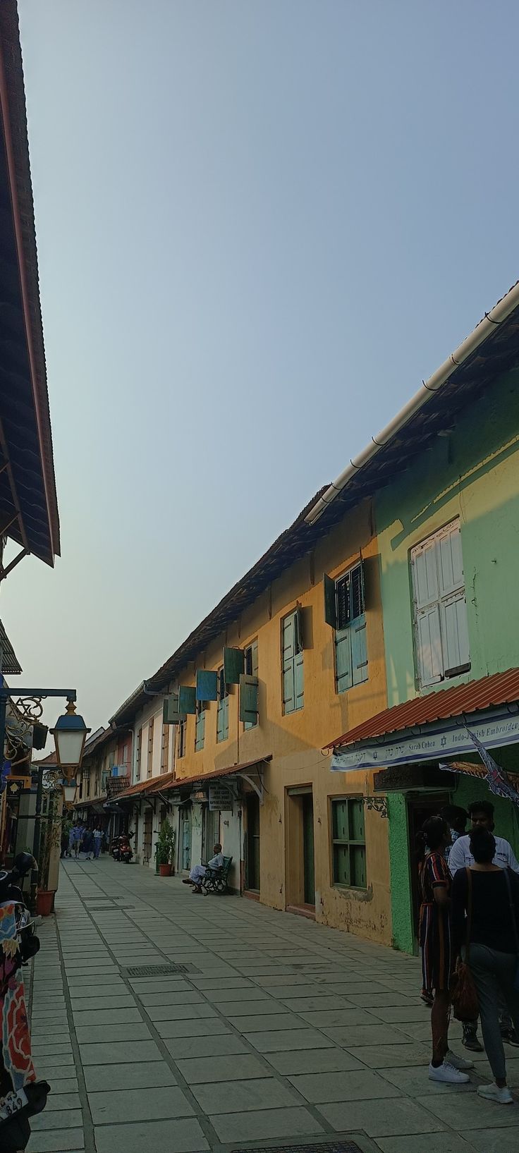 people are walking down the street in front of some colorful buildings with shutters on them