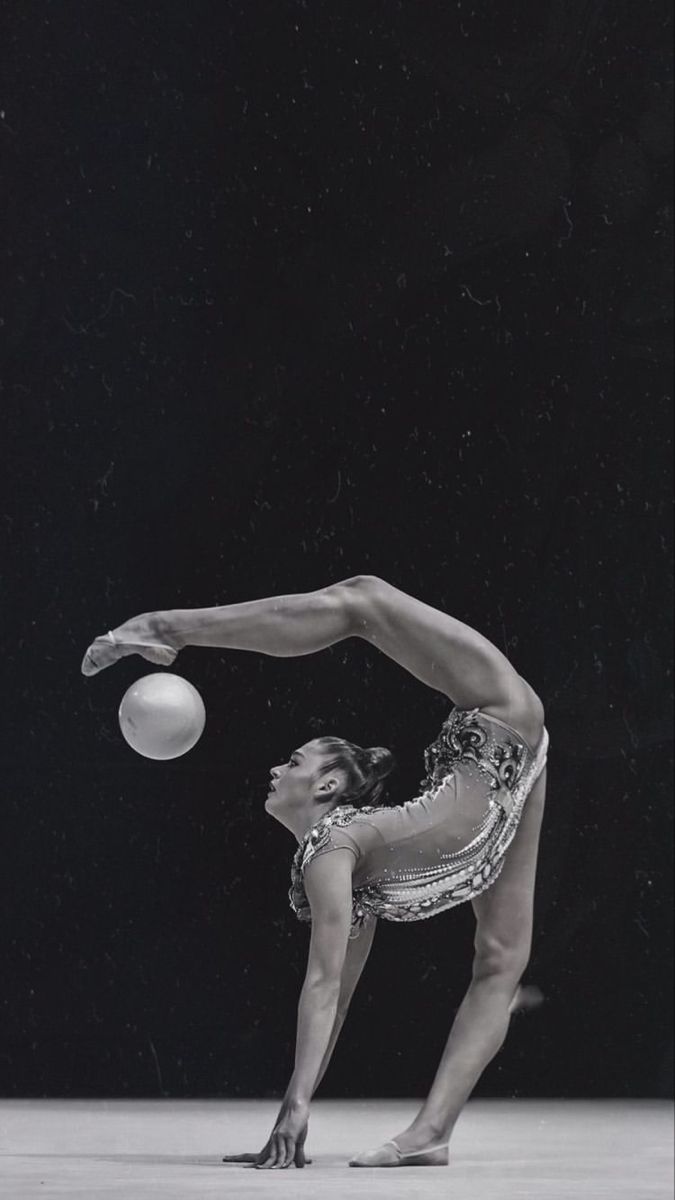 a woman is doing an acrobatic trick with a ball