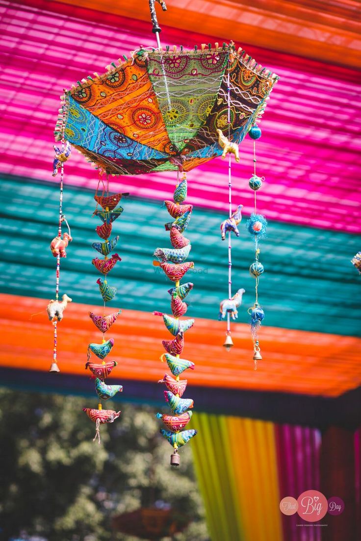 an umbrella with beads hanging from it's side in front of a colorful structure