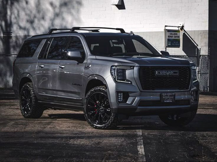 a silver truck parked in front of a white building with black rims on it