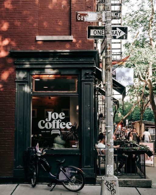 a bicycle parked on the side of a street next to a pole with a sign that says joe coffee