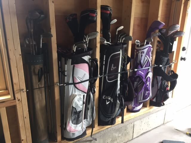 several different types of golf clubs are lined up in a storage area on the wall