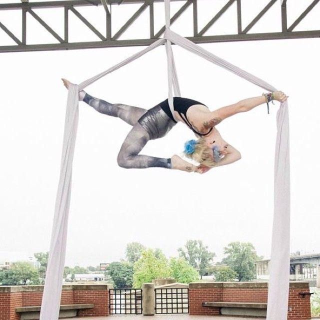 a woman is performing aerial acrobatics on a pole