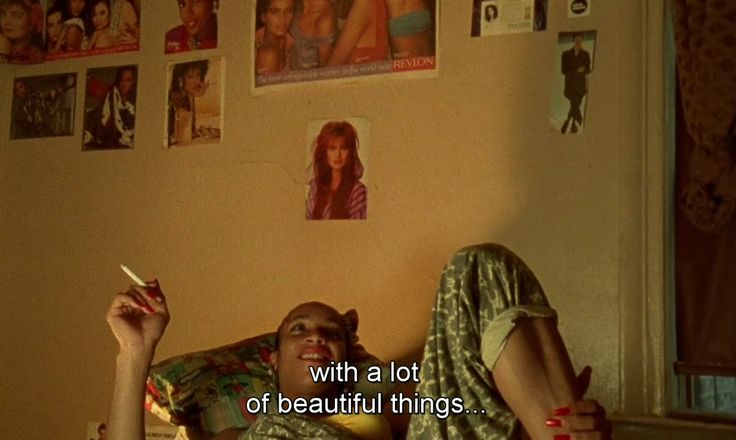 a woman laying on top of a bed next to a wall covered in pictures and text