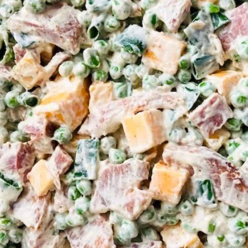 a close up view of a salad with peas and ham