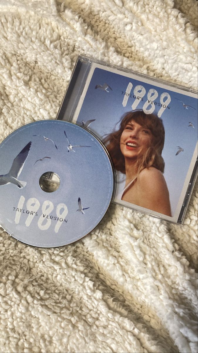 a cd sitting on top of a white blanket next to a dvd case with an image of a woman's face