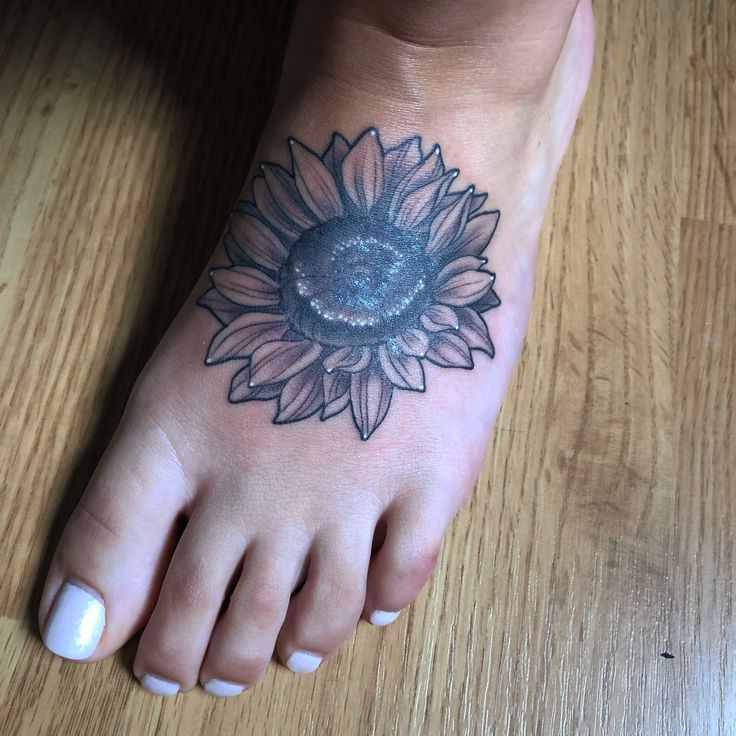 a sunflower tattoo on the foot of a woman