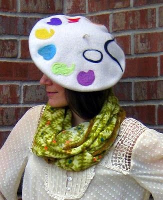 a woman wearing a hat and scarf with buttons on the side, standing in front of a brick wall