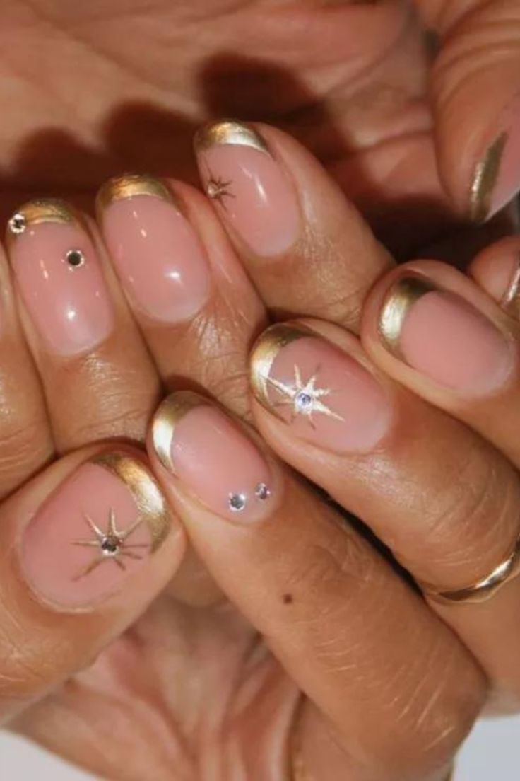 You can never go wrong with a French manicure. The classic nail art idea is even better when painted in matte gold polish and topped off with sparkling gemstones. Pink And Gold French Manicure, Silver And Gold Manicure, Gold Star Nail Design, Celestial Short Nails, French Tip With Gold Stars, Gold Nails Summer, Wedding Guest Nail Art, Gold French Manicure, Gold French Tips