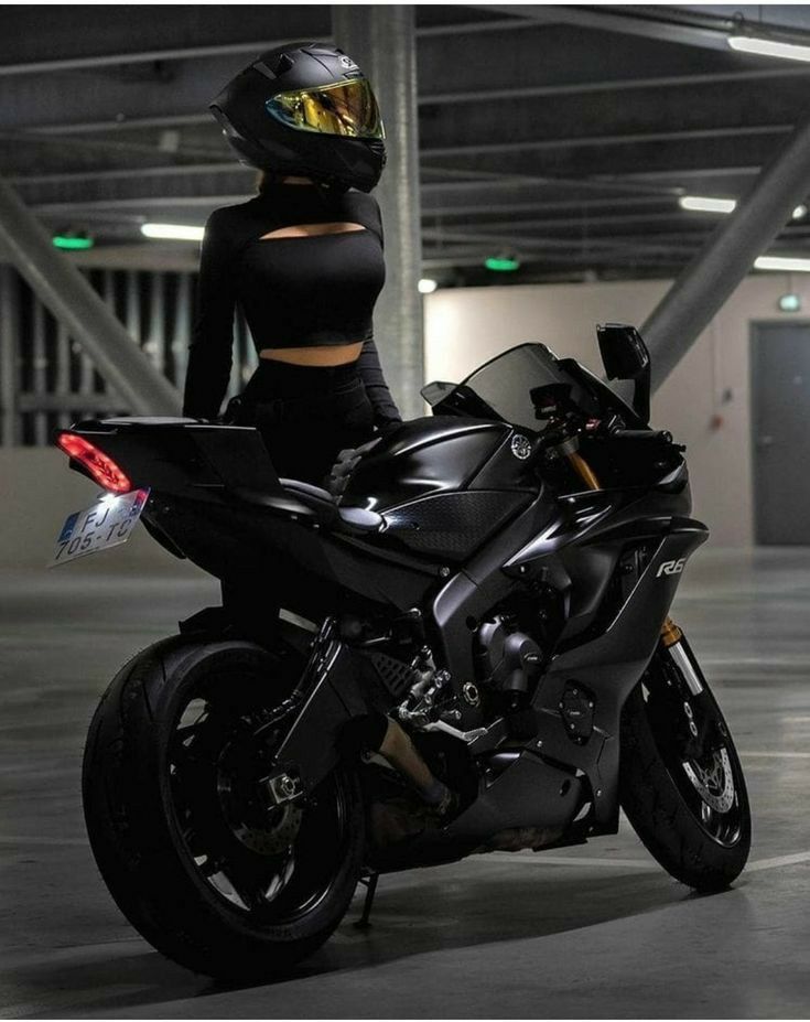 a woman is sitting on a motorcycle in a parking garage wearing a helmet and black tights