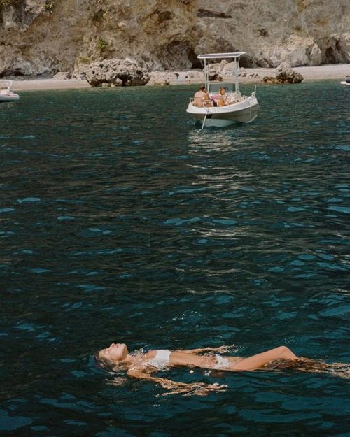 two people floating in the water near a boat