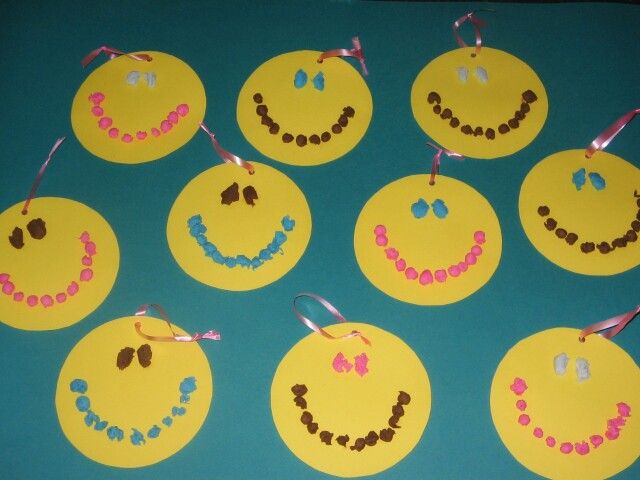 paper circles with smiley faces on them are hanging from ribbon and decorated with beads in the shape of letters