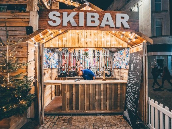 an outdoor ski bar is lit up at night with lights on the roof and wooden walls