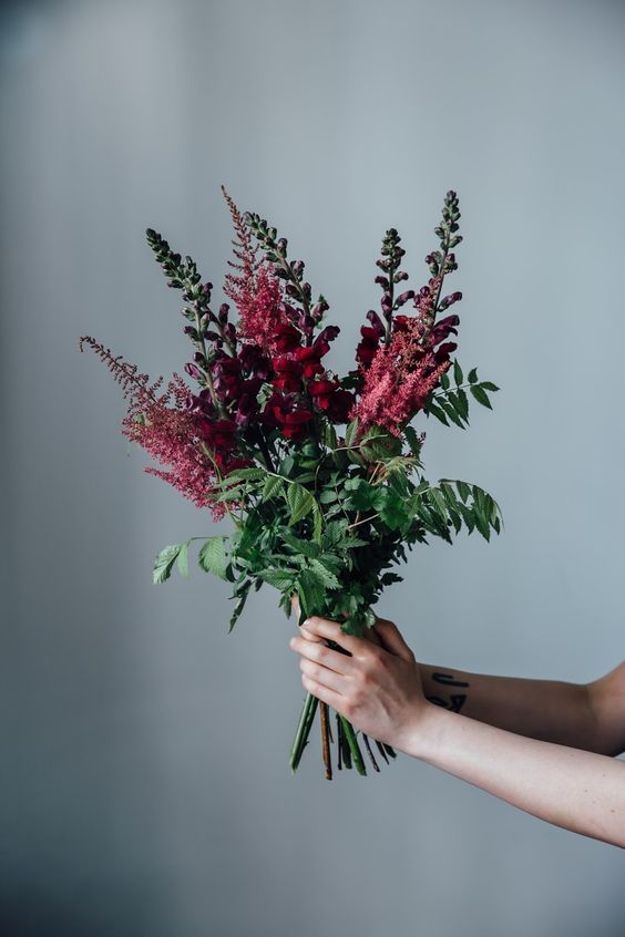 a woman holding a bouquet of flowers in her hand with the stems still attached to it