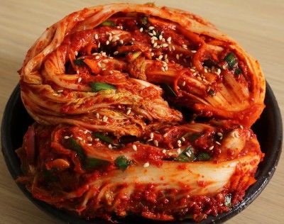 a black bowl filled with noodles and sauce on top of a wooden table