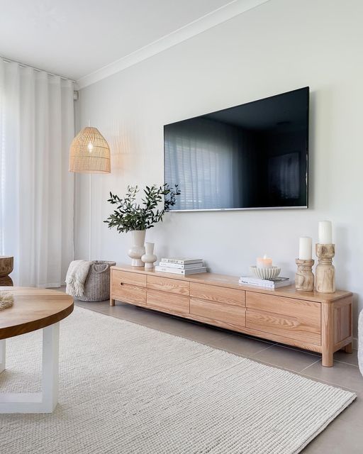 a flat screen tv mounted on the wall above a wooden table in a living room