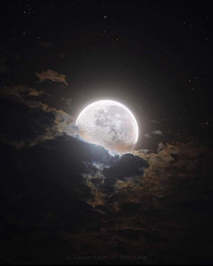 the full moon is shining brightly in the night sky with clouds and stars around it