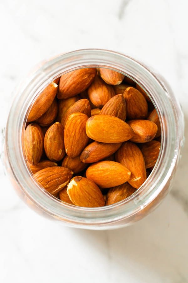 almonds in a jar with text overlay that reads oven roasted almonds and how to use them