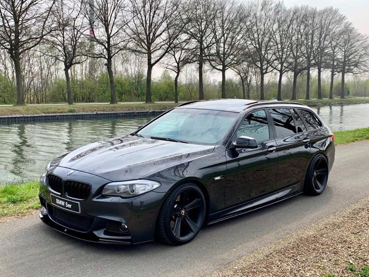 a black car parked on the side of a road next to a body of water