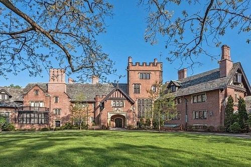 a large brick house with lots of windows on the front and side of it, surrounded by lush green grass