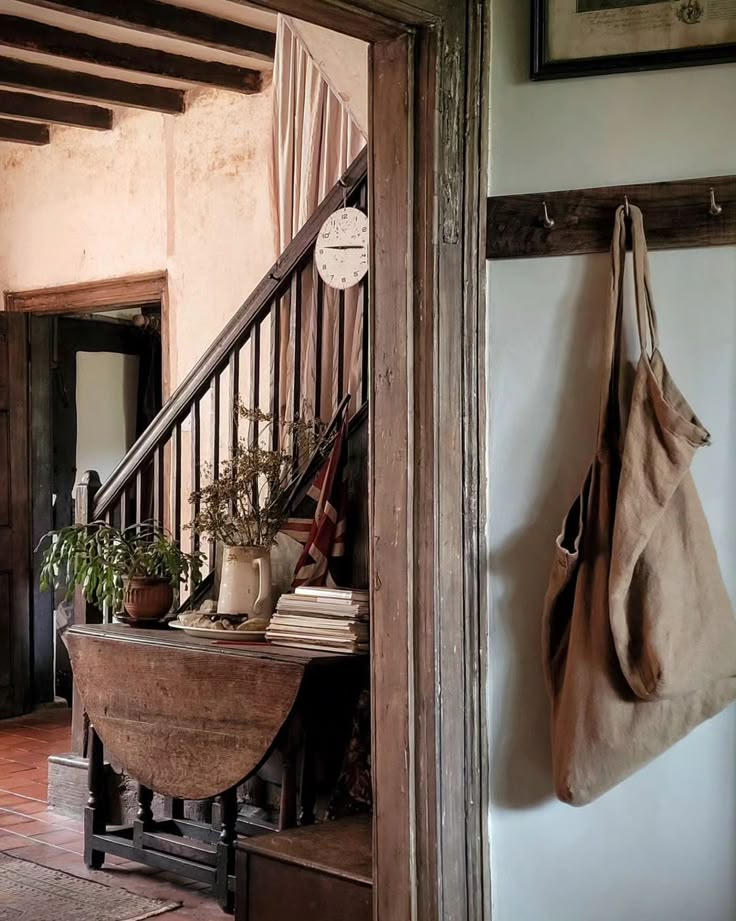 a wooden table sitting under a stair case next to a wall mounted potted plant