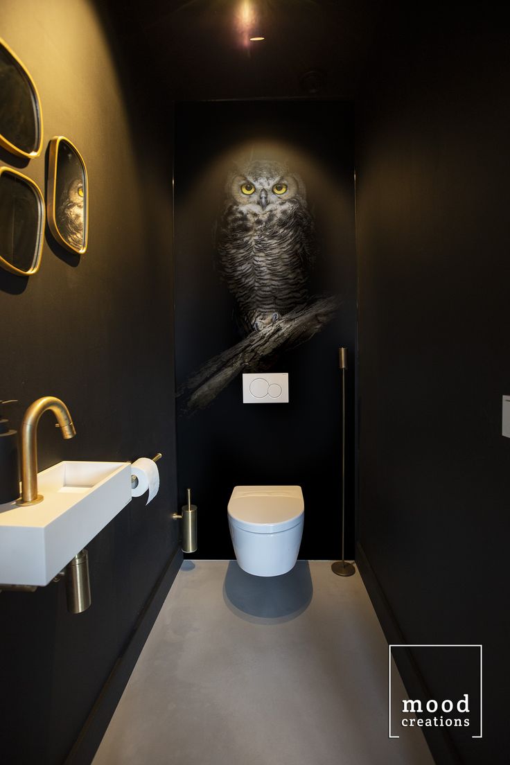 a toilet and sink in a small room with an owl on the wall above it