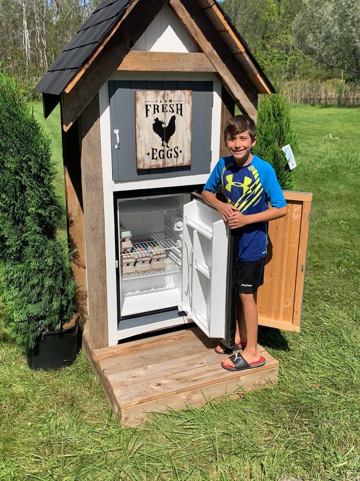 a young boy stands in front of an icebox with the door open and it's freezer inside