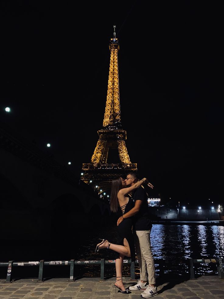 a man and woman standing in front of the eiffel tower