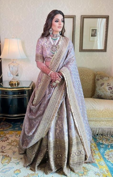 a woman standing in a room wearing a purple and gold outfit with jewelry on her neck