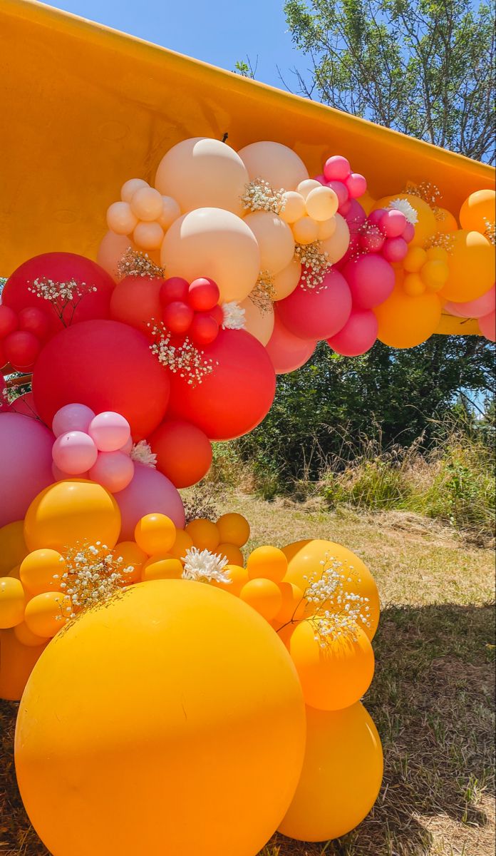 balloons and other decorations are hanging from the side of a yellow boat in an open field